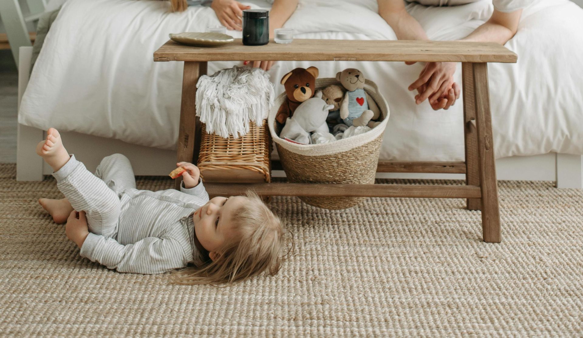 Family bonding time in a cozy bedroom with parents playing with child on the floor.