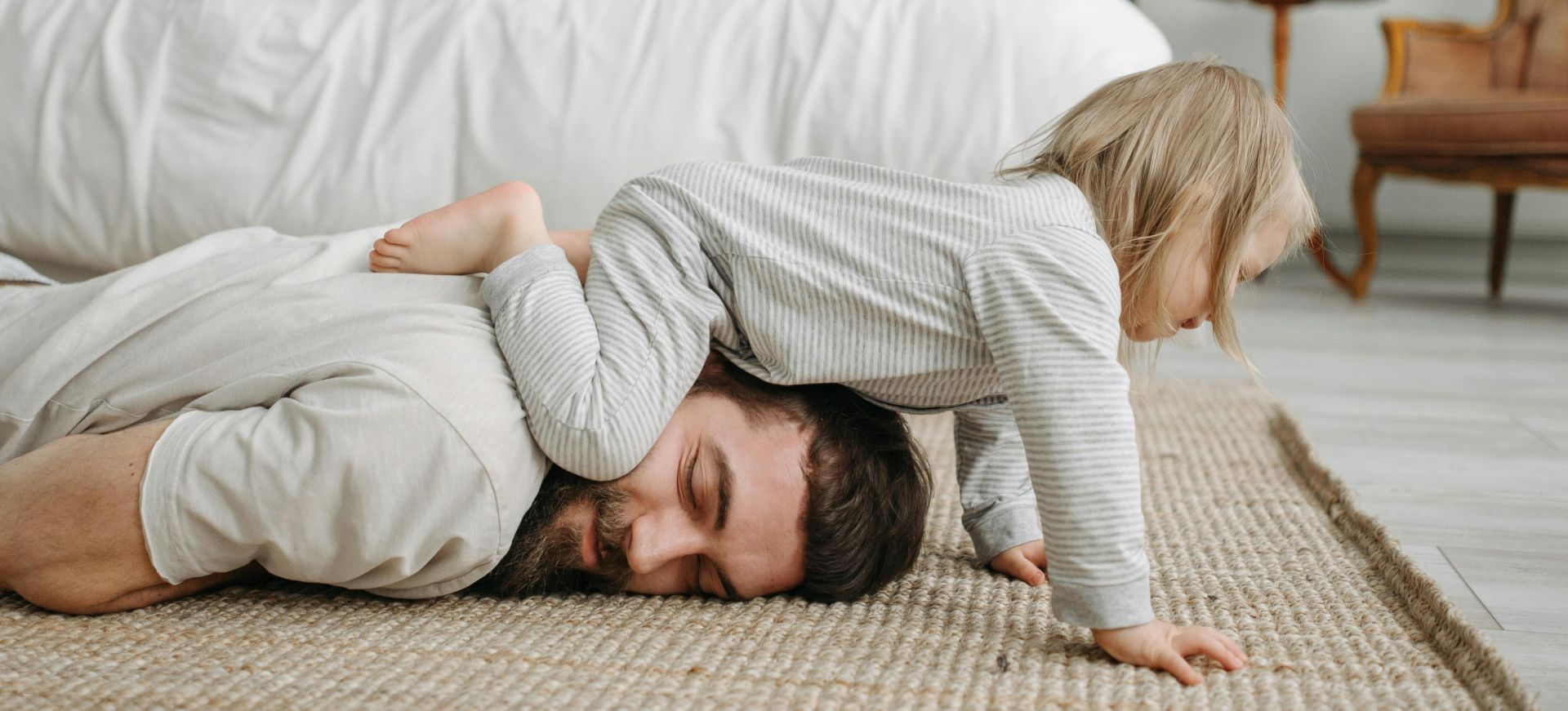 Father playing with daughter indoors, enjoying quality family time on the carpet.